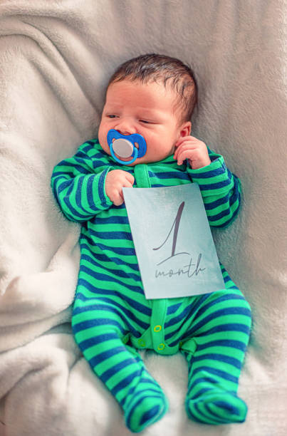 Cute baby with 1 month old milestone card in his hand Cute baby with 1 month old milestone card in his hand monthly event photos stock pictures, royalty-free photos & images