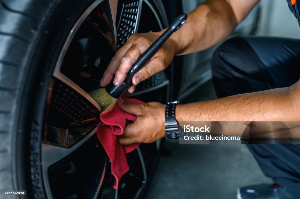 Professional worker cleaning car rim Professional car service worker polishing luxury car rim with a microfiber rag. Car Detailing Stock Photo