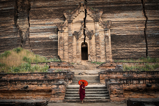 A novice Buddhist monk visits the ancient ruins of Mingun Pahtodawgyi Pagoda in Sagaing, Mandalay, Myanmar (Burma).
