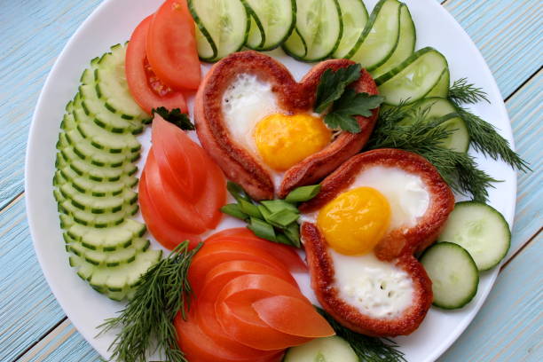 café da manhã para o dia dos namorados com ovos de salsicha em forma de coração e legumes. - eggs breakfast heart shape fried egg - fotografias e filmes do acervo