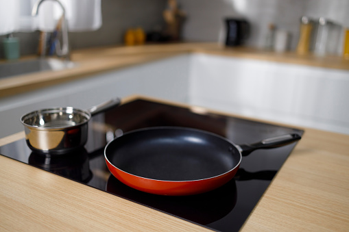 Frying pan and sauce pan on induction hob in modern kitchen