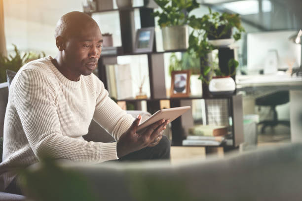 istock A man using a digital tablet while relaxing on the sofa at home. A young man browsing online with a touchscreen on the couch 1399934606