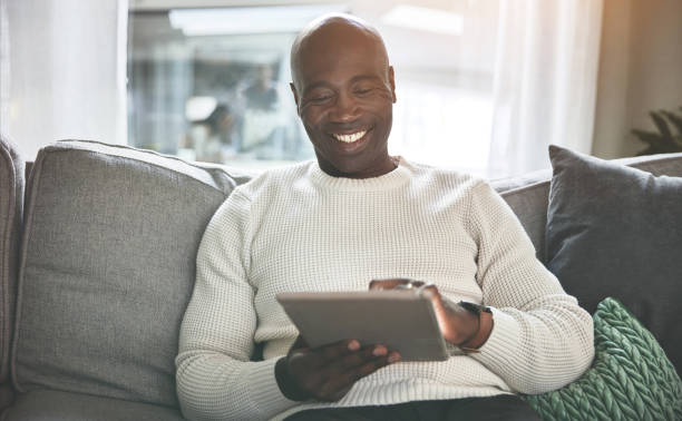 istock A man using a digital tablet while relaxing on the sofa at home. A happy young man browsing online with a touchscreen on the couch 1399934620