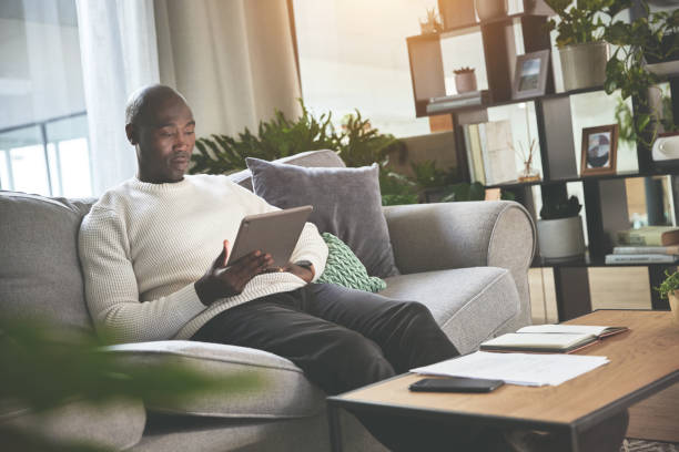 istock A man using a digital tablet and working with paperwork at home. A young man paying bills, planning his finance online with a touchscreen on the sofa 1399934950