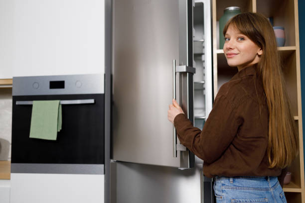 istock Cute girl opens the refrigerator in the kitchen 1399935918