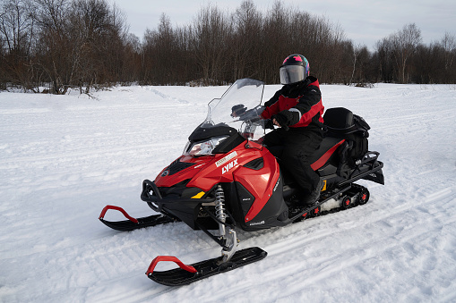 Rovaniemi, Finland - March 20th, 2022: A tourist preparing for a snowmobile tour on a frozen river in Finland.