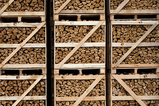 Chopped dry firewood stacked in large wooden containers. Dry chopped firewood. Background from dry chopped firewood. Ready firewood for sale at the warehouse