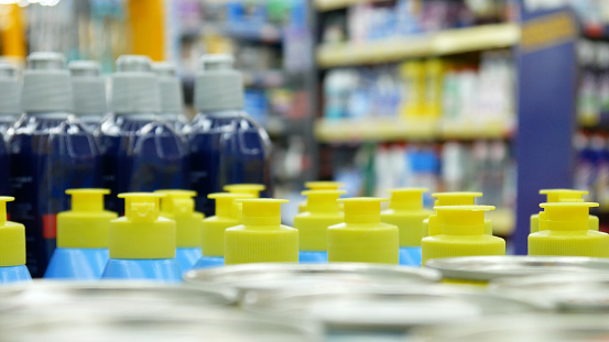 Many bottles of dishwashing liquids and detergents on a store counter close-up