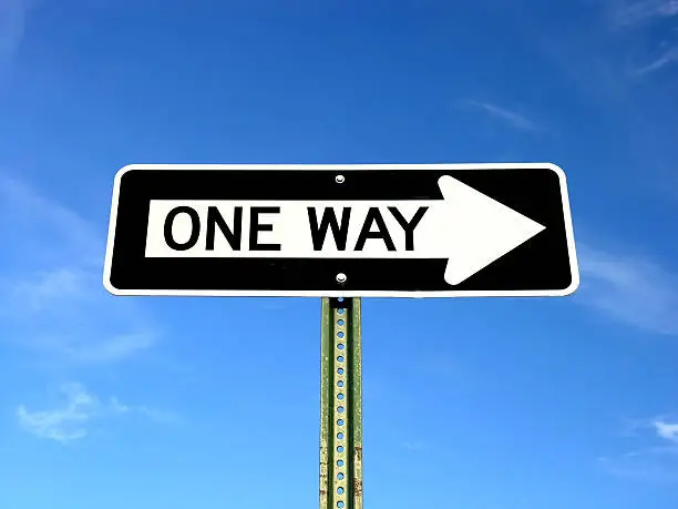 One way sign isolated against a blue sky