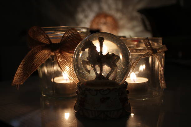 close up of a snow ball, with a toy horse, with backlight of candles, in a Christmas mood