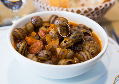 Tasty home style snails stewed with chorizo sausages in tomato sauce