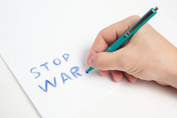 istock Hand with ballpoint pen and inscription stop war white background. 1399942070