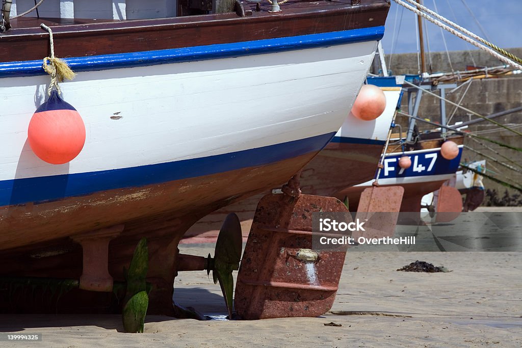 Boat Rudders at Low Tide Shot of props and rudders of fishing boats at low tide Anchor - Vessel Part Stock Photo