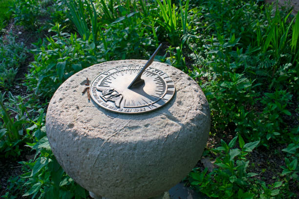 Sun Dial at Colonial Park Gardens Metallic sundial set in stone on a bed of various green plants and grasses on a sunny day ancient sundial stock pictures, royalty-free photos & images