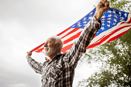 Parents with cute little children enjoying July 4th picnic, holding american flags.