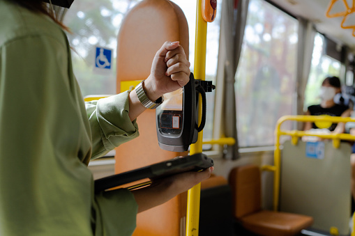 Everyday life and commuting to work by bus. Unrecognizable businesswoman is paying transport ticket with smartwatch