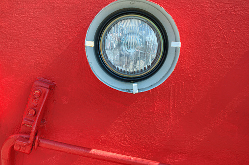 View of the headlight, part of an old locomotive close-up, piece of machinery. Red painted metal