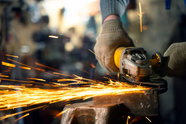 istock Locksmith in special clothes and goggles works in production. Metal processing with angle grinder. Sparks in metalworking 1399949355