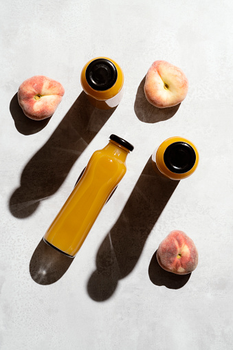 Peach juice and peaches, directly above, table top shot. Fresh fruit juice in glass bottle and drinking glass.
