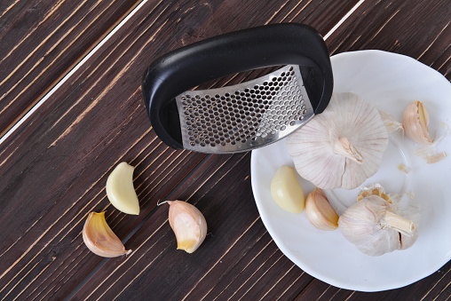 Garlic press and cloves of garlic