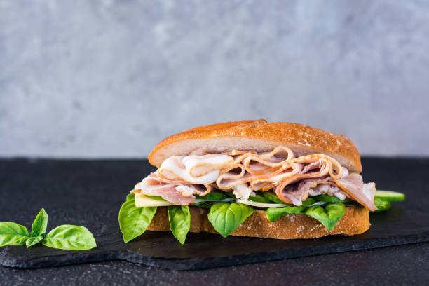 istock Appetizing sandwich with pastrami, cucumber, cheese and basil on the table. Copy space 1399952947