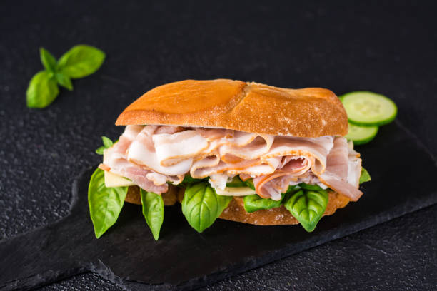 istock Appetizing sandwich with pastrami, cucumber, cheese and basil on the table. Home fast food. 1399952949