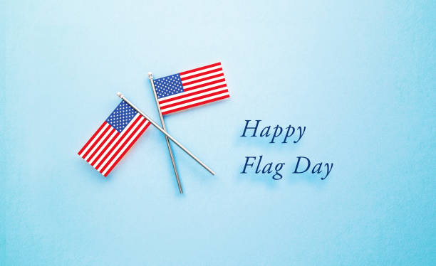 istock Happy Flag Day Message Sitting Next to Tiny American Flag Pair  on Blue Background 1399956290