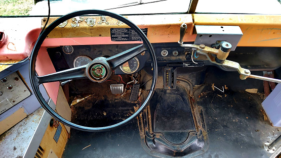 Old bus driver side with steering wheel, throtle and brake comparment. Old bus driver compartment with driving instruction plate.