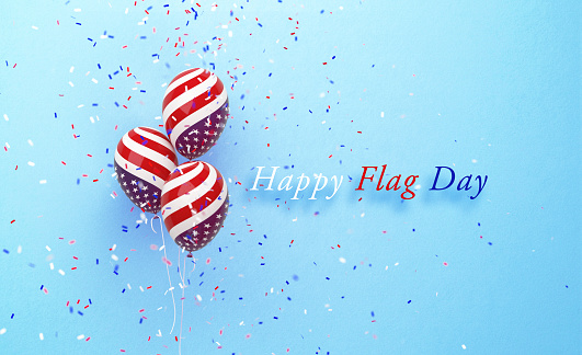 Happy Flag Day Day message sitting next to balloons textured with American flag on blue  background. Horizontal composition with copy space. Front view.