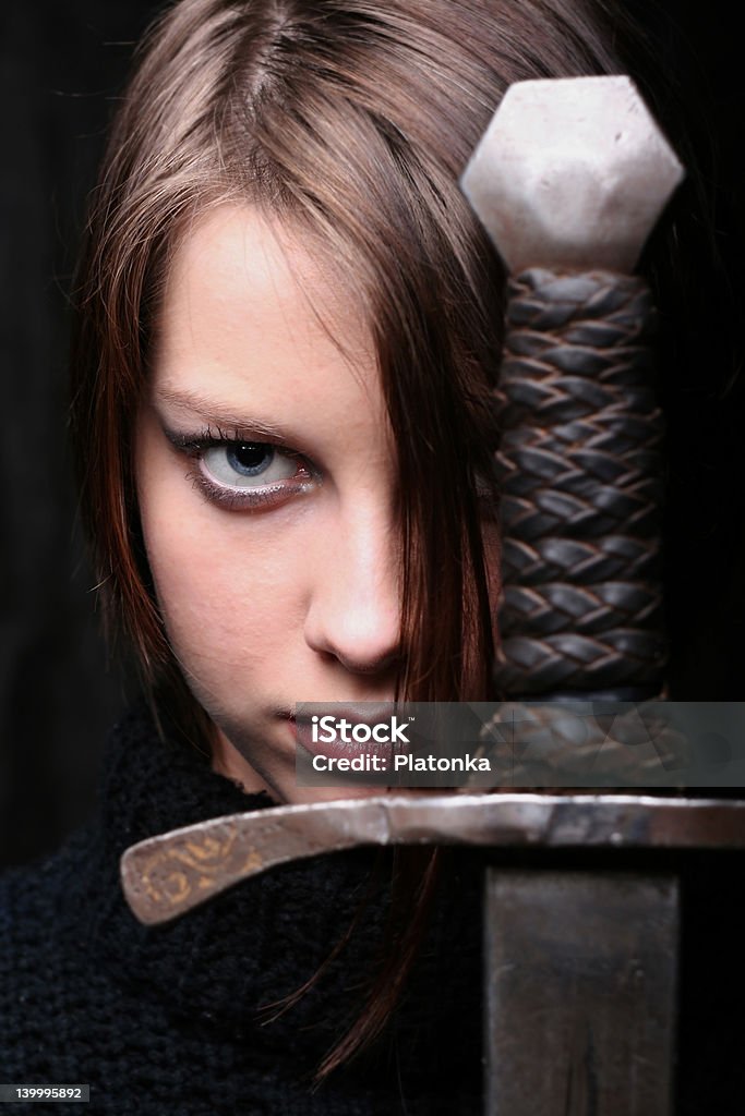 GIRL WITH SWORD Standing in self defense. Soft skin contrasts cold metal. Bible Stock Photo