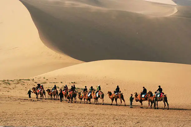 Tourists ride camels at Mingsha Shan (Singing Sand Dunes) in Dunhuang, China