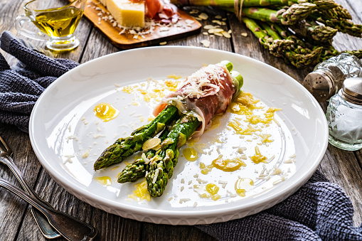 Cooked green asparagus and parmesan on wooden background