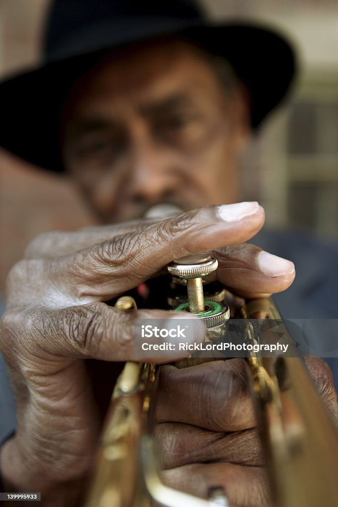 Playing the Blues Black man with a hat playing an old French Quarter trumpet. New Orleans Stock Photo