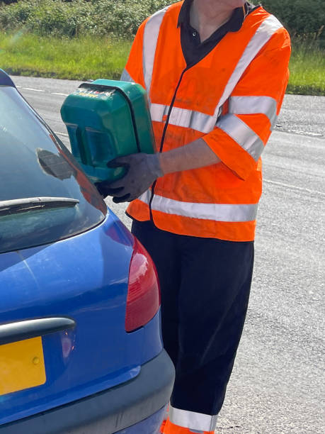 imagem de close-up de carro azul quebrado na beira da estrada, reabastecendo tanque de combustível com lata de combustível jerry, assistência de quebra de veículo, mecânico de carro vestindo reflexivo, jaqueta de alta visibilidade - gas can stranded car gasoline - fotografias e filmes do acervo