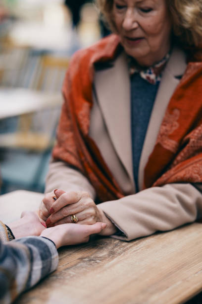 uma avó se conectando com sua neta enquanto estava sentada no café e de mãos dadas. - generation gap multi generation family vertical holding hands - fotografias e filmes do acervo