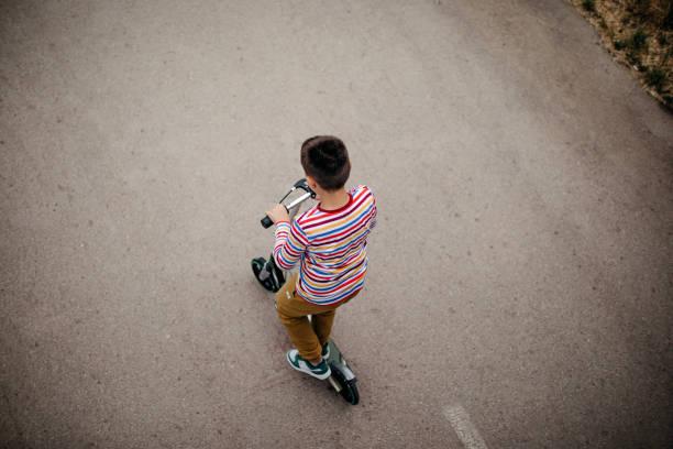 Single boy riding a push scooter