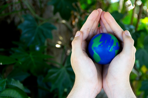 Hands holding an earth on an out-of-focus background of green plants, Concept of the Environment , World Earth Day.