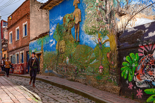 Bogota, Colombia - May 28, 2017: Local Colombian people walk down the narrow, cobblestoned Calle del Embudo which gets its name from its shape. The English translation of the name would be, 