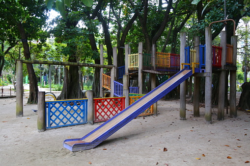 City of Santo André, Brazil. Public park with lots of greenery and children's playground with stairs and colorful slides in the middle of urban life.
