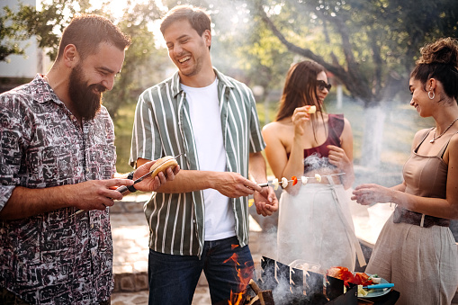 Group of young barbecues in the yard by the pool