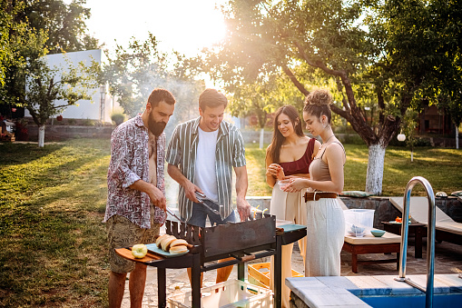 Group of young barbecues in the yard by the pool