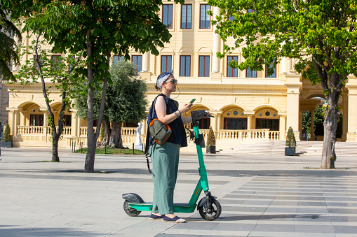 Young woman driving an electric scooter in the city. She looks happy.