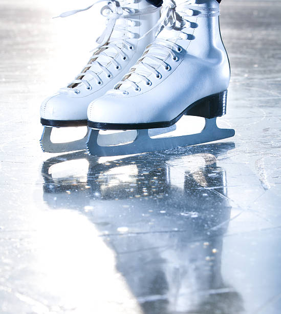 On a white background there are two pairs of skates with white laces and white soles. Ice skates are positioned in such a way that they appear ready for use.