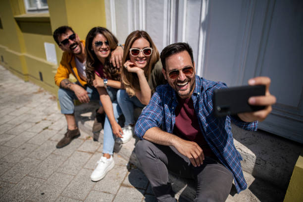 istock Cheerful friends sit on the steps and take selfies 1399976620