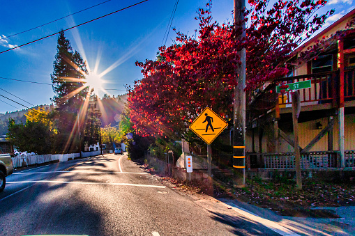 Guerneville, United States - November 12 2011 : the main street and cars in small town in Russian River at a weekend morning with a pedestrian sign