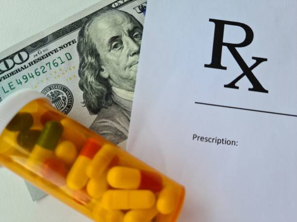 薬の入ったドル紙幣と医師の処方箋は、診療所のクローズアップで医師のテーブルに横たわっています - rx ストックフォトと画像