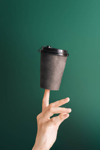 istock Dark cup on the index finger against green background 1399991946