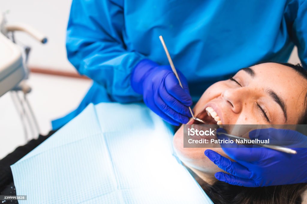 Unrecognizable dentist doing a routine dental checkup using a mouth mirror and an excavator, to a female patient Unrecognizable dentist doing a routine dental checkup using a mouth mirror and an excavator, to a female patient. Dental care. Horizontal. Copy space Dentist Stock Photo