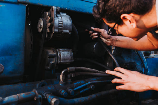 istock Latin farmer man repairing mechanical problems of an old blue tractor. 1399994529