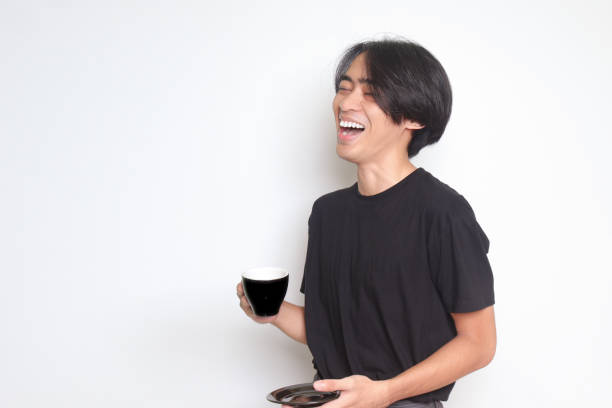 istock Asian man laughing out loud while holding a saucer and a coffee cup 1399995630